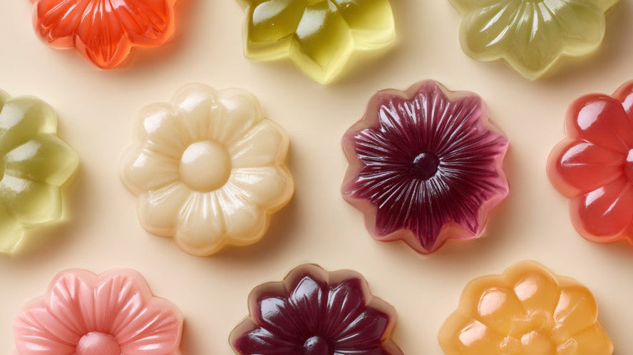 Bonbons gélifiés colorés en forme de fleurs, disposés sur une surface beige.